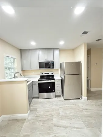 a kitchen with a refrigerator a stove top oven and cabinets
