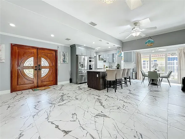 a kitchen with stainless steel appliances kitchen island granite countertop a sink dishwasher a stove a refrigerator and a dining table with wooden floor