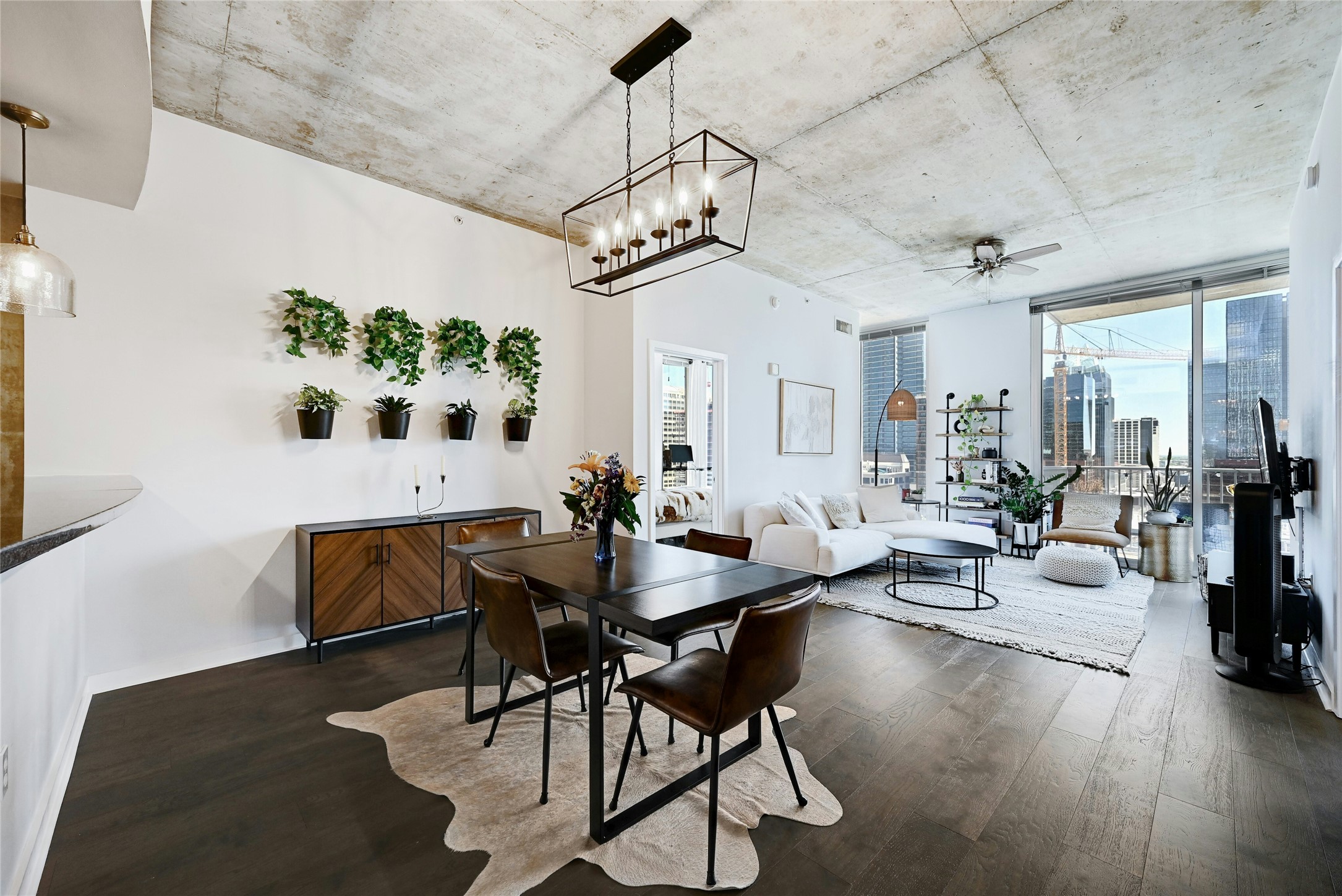 360 Nueces Street, Unit 1809 Austin, TX 78701 - Photo 3 of 25 Open-concept living and dining area featuring dark wood-finish flooring, concrete ceilings, and a linear chandelier