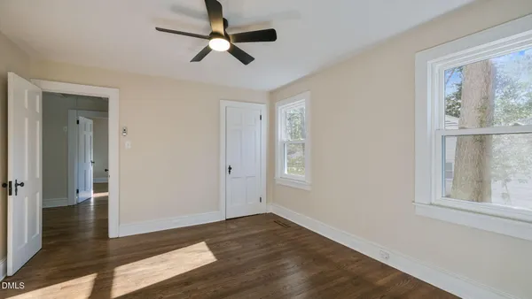 an empty room with wooden floor cabinet and windows