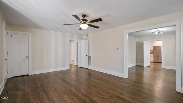 a view of an empty room with wooden floor and a window