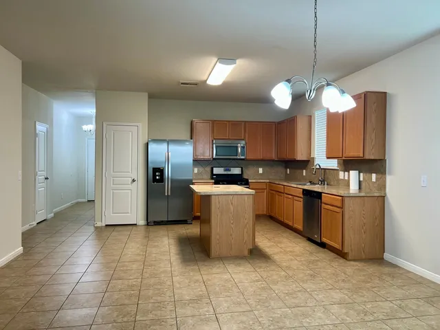 a kitchen with stainless steel appliances granite countertop a refrigerator a sink a stove and a oven