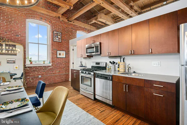 a kitchen with stainless steel appliances granite countertop a stove top oven a sink dishwasher and white cabinets with wooden floor