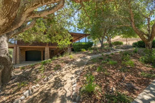 a backyard of a house with table and chairs under an umbrella