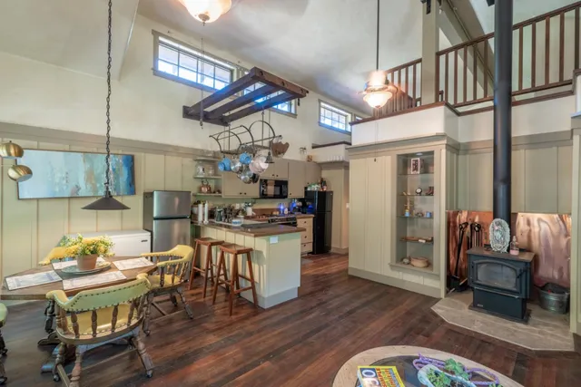 a kitchen with stainless steel appliances kitchen island granite countertop a table chairs in it and a wooden floor