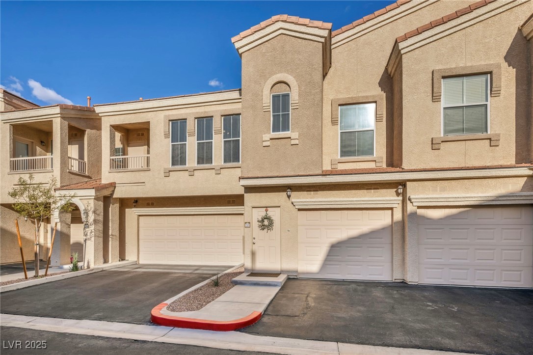 10550 West Alexander Road, Unit 2103 Las Vegas, NV 89129 - Photo 1 of 45 View of property featuring a tiled roof, a garage, stucco siding, and aphalt driveway