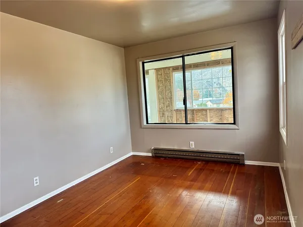 a view of empty room with wooden floor and fan