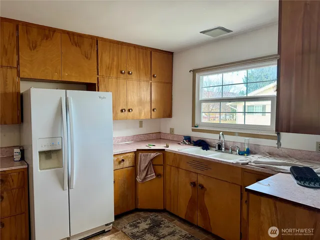 a kitchen with a sink a refrigerator a window and cabinets