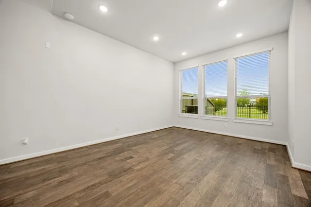 a large white kitchen with a refrigerator a sink dishwasher a stove and a dining table with wooden floor