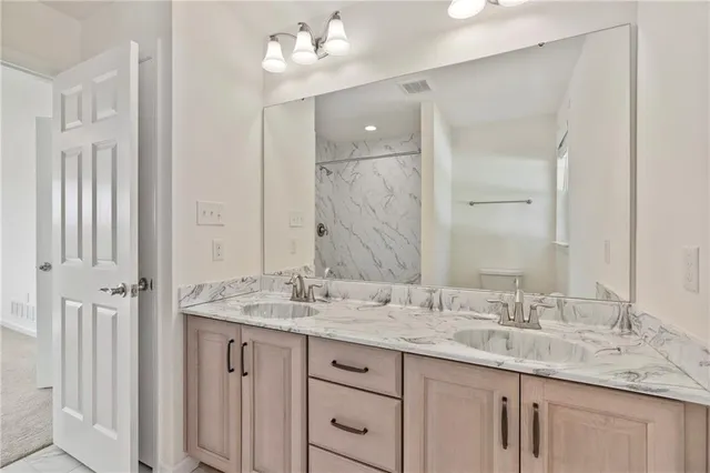 a bathroom with a granite countertop double vanity sink and a mirror