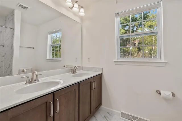 a bathroom with a granite countertop sink a large mirror and a window