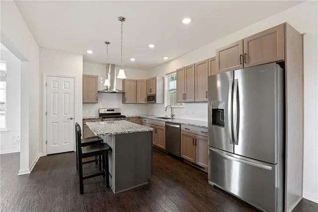 a kitchen with stainless steel appliances granite countertop a refrigerator a sink dishwasher a stove and white cabinets with wooden floor