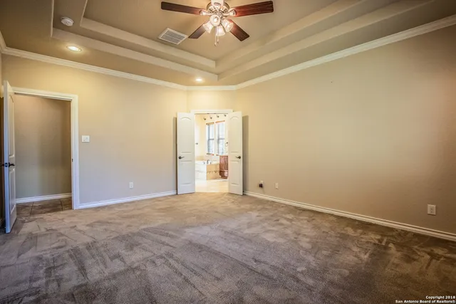 a view of an empty room and chandelier fan