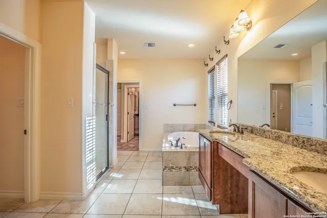 a spacious bathroom with a granite countertop sink a mirror and a shower
