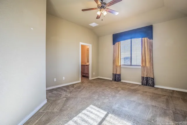 an empty room with windows and fan