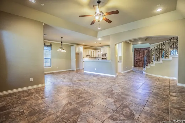 a view of a livingroom with a chandelier fan and kitchen view