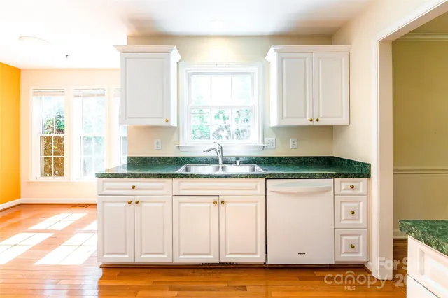 a kitchen with granite countertop white cabinets and window