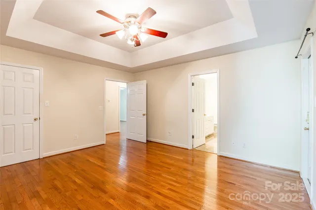 an empty room with wooden floor and a ceiling fan