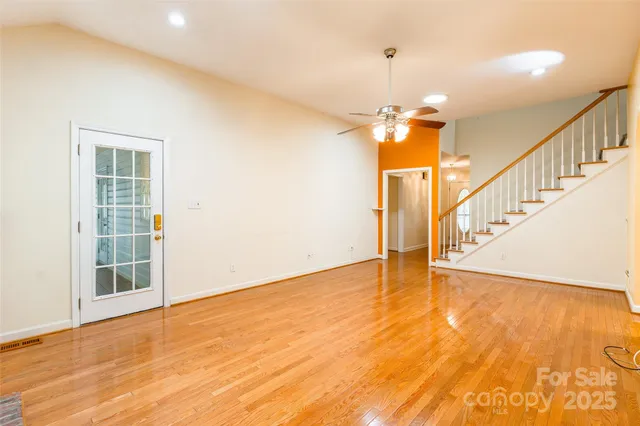 a view of empty room with wooden floor and fan