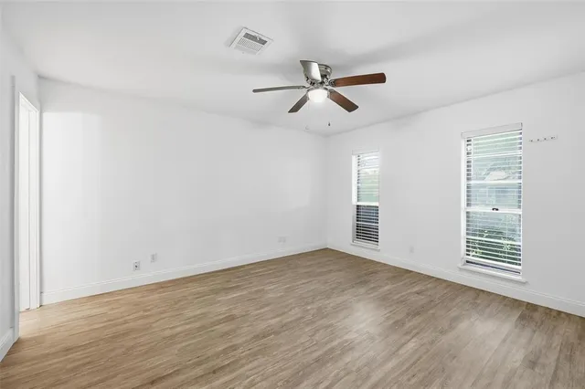 an empty room with wooden floor closet and windows