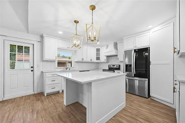 a kitchen with kitchen island white cabinets and stainless steel appliances