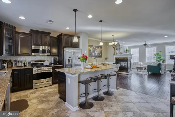 a kitchen with stainless steel appliances kitchen island granite countertop a stove a sink a oven a dining table with chairs and cabinets
