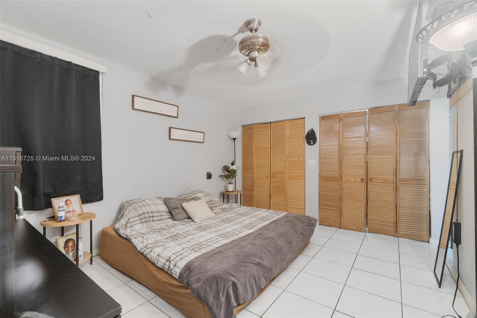 1900 West 68th Street, Unit E104 Hialeah, FL 33014 - Photo 17 of 31 a bedroom with a large bed and a chandelier