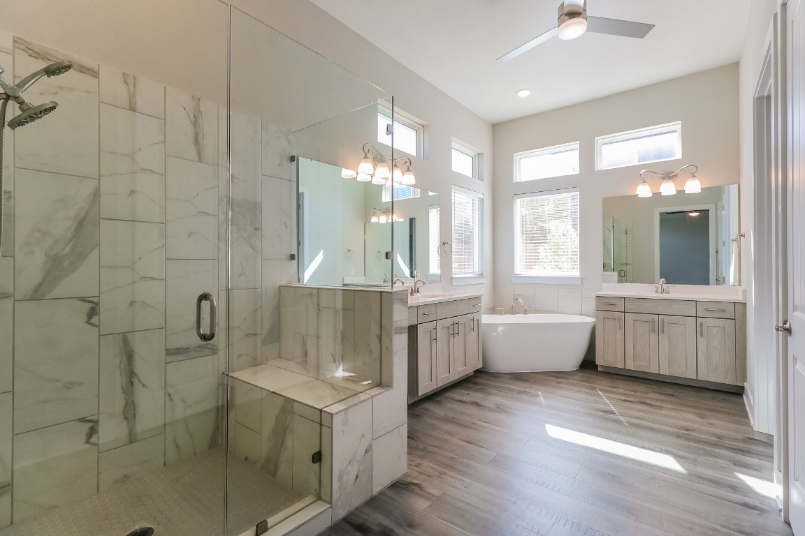 6101 Antelope Well Lane Austin, TX 78738 - Photo 17 of 36 a bathroom with a double vanity sink a large mirror and bathtub