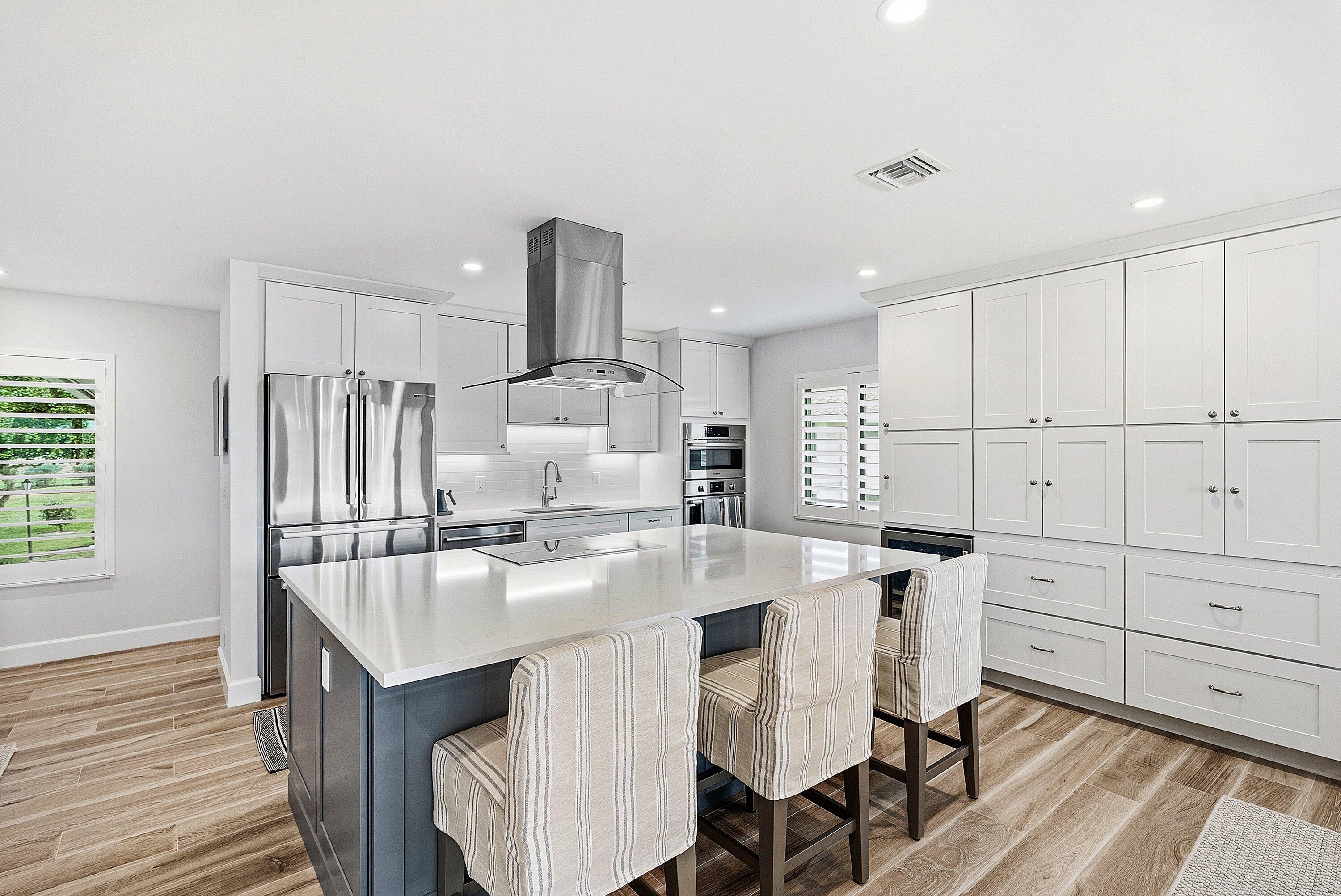 10157 Quail Covey Road, Unit HIBISCUS N Boynton Beach, FL 33436 - Photo 2 of 52 a kitchen with kitchen island a stove a table and chairs in it