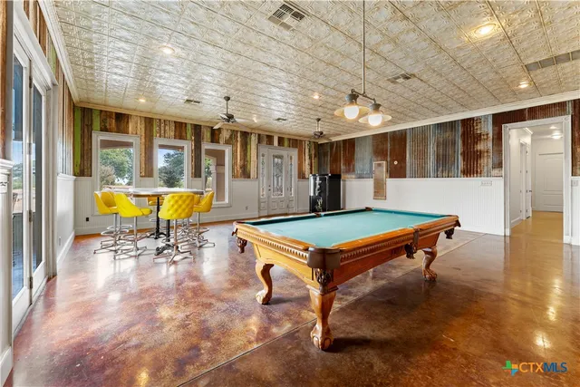 a room with furniture pool table wooden floor and windows