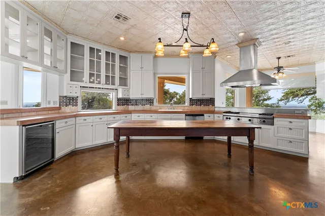 a room with stainless steel appliances kitchen island granite countertop a stove a sink and a chandelier