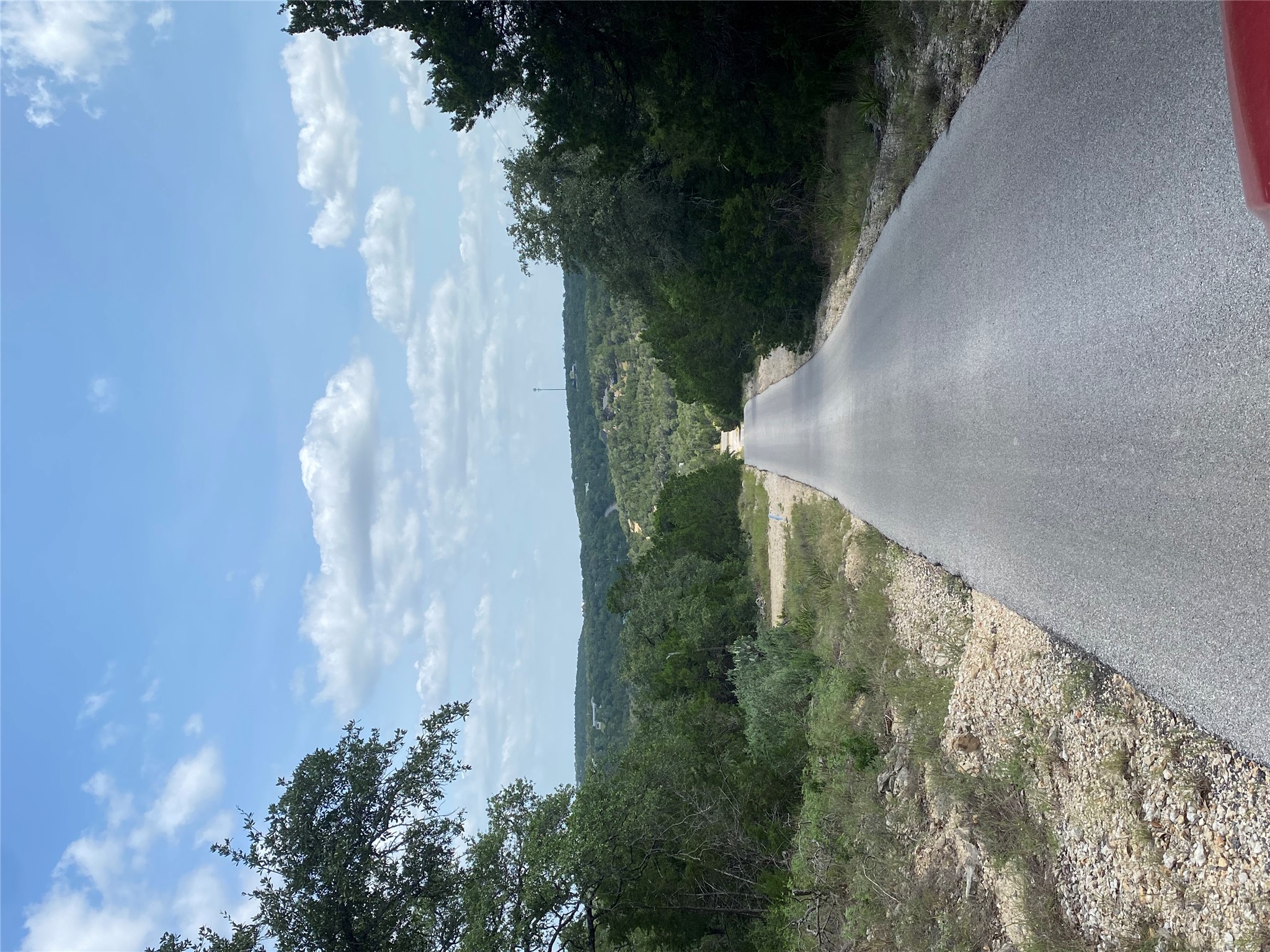 Tbd Whisper Ridge Wimberley, TX 78676 - Photo 1 of 7 A long, winding paved driveway leads through a wooded landscape, offering picturesque views of distant hills.