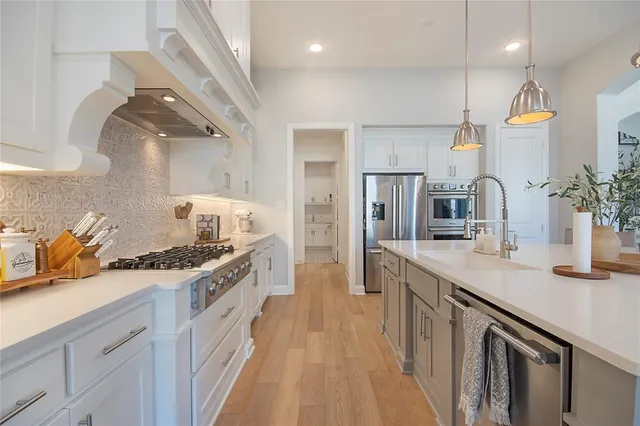 a kitchen with stainless steel appliances granite countertop a sink a stove and a refrigerator