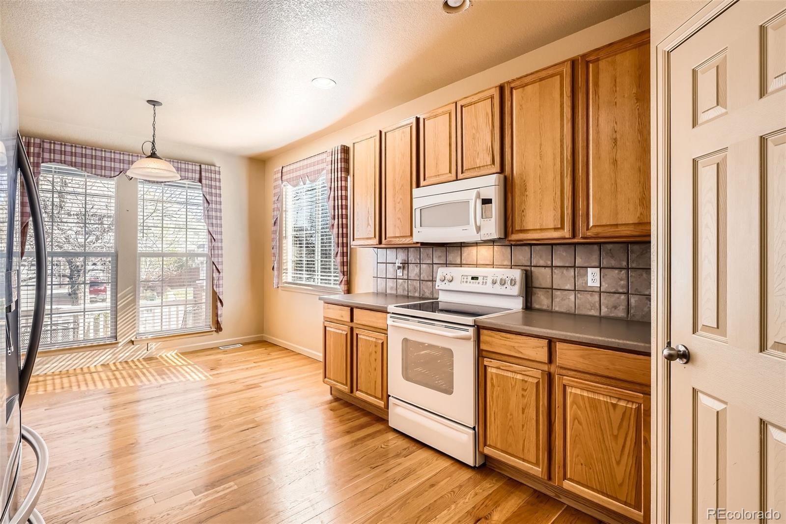 1978 Granger Circle Castle Rock, CO 80109 - Photo 10 of 31 a kitchen with stainless steel appliances granite countertop a stove a sink and white cabinets with wooden floor