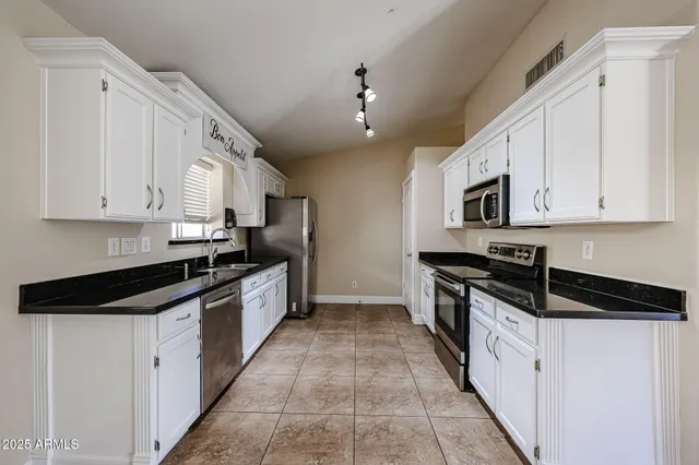 a kitchen with granite countertop white cabinets and a sink