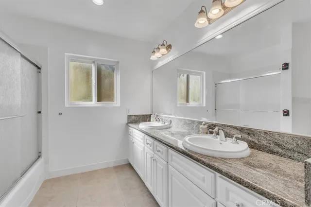 a bathroom with a sink double vanity granite and a mirror