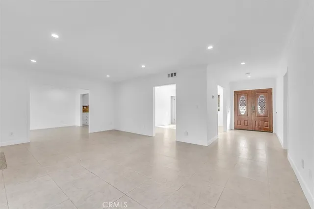 a view of an empty room with wooden floor and windows