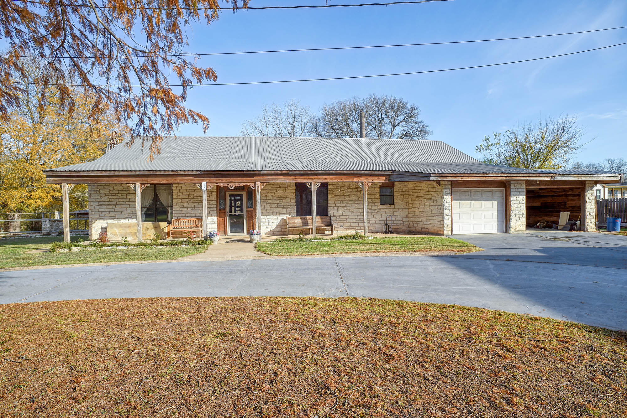 113 My Road Bastrop, TX 78602 - Photo 7 of 35 Ranch-style house featuring stone siding, an attached garage, a porch, and concrete driveway