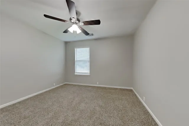 an empty room with a window and a fan