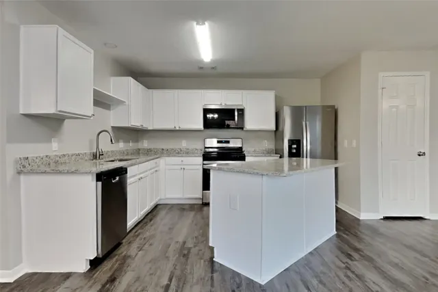 a kitchen with granite countertop a refrigerator stove top oven and sink