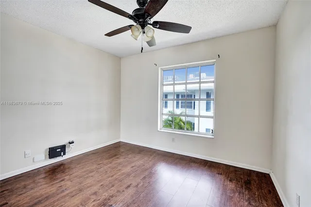 an empty room with wooden floor chandelier fan and windows
