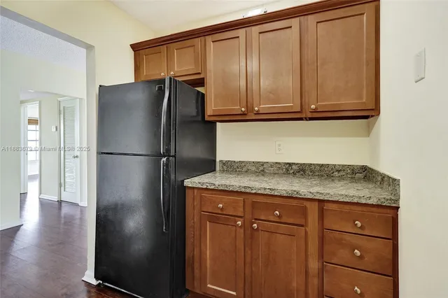 a kitchen with granite countertop stainless steel appliances a refrigerator and cabinets