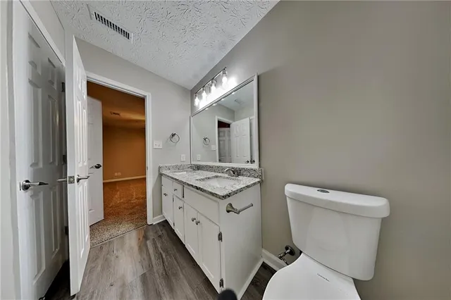 a bathroom with a granite countertop toilet and a sink