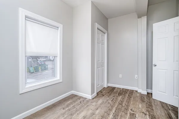 a view of an empty room with window and wooden floor