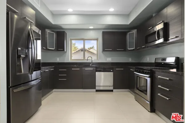 a kitchen with stainless steel appliances granite countertop a stove a sink and a refrigerator