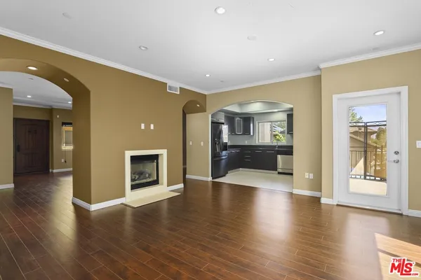 a view of an entryway of a house and empty room with wooden floor