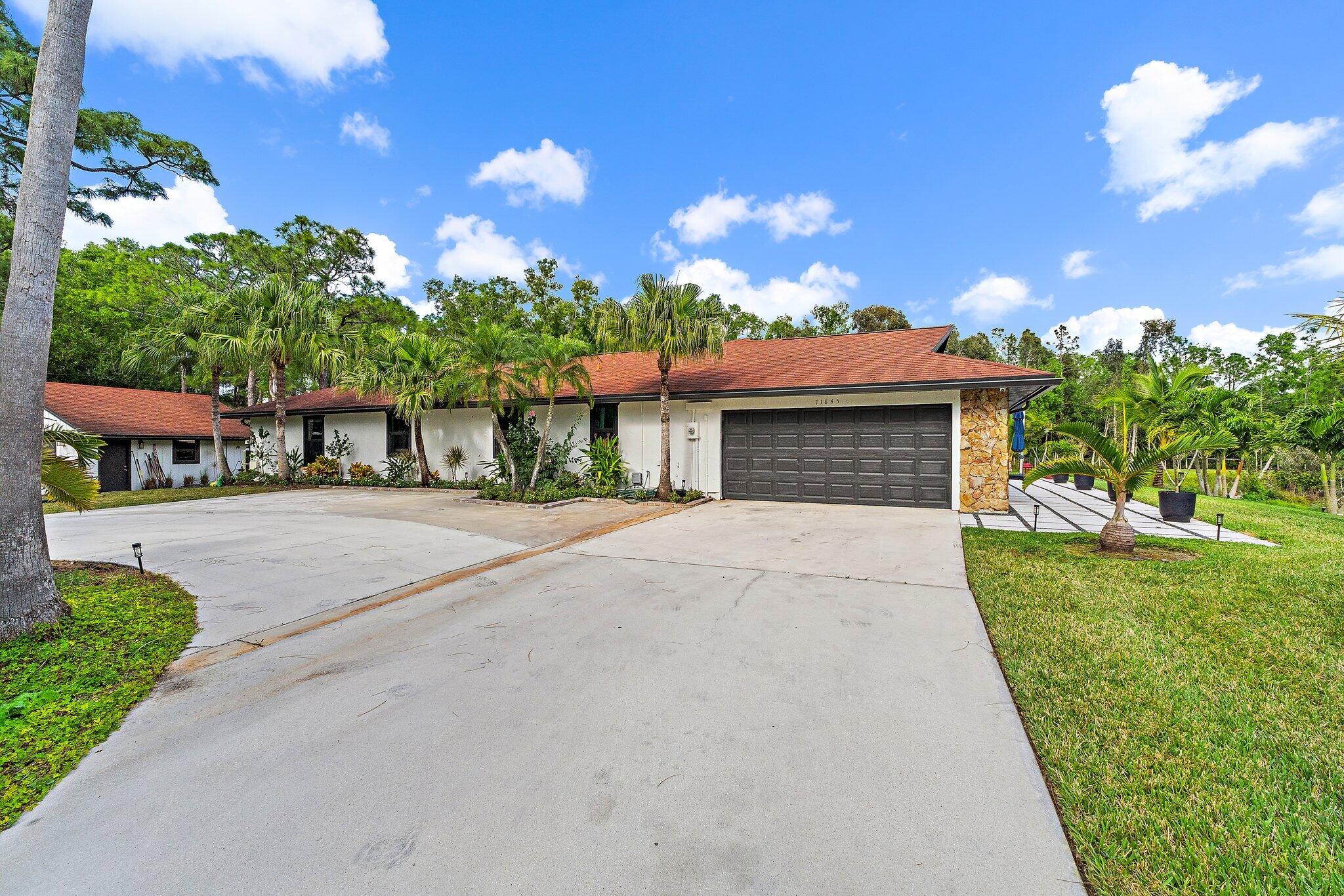 11845 165th Road North Jupiter, FL 33478 - Photo 8 of 68 a front view of a house with a yard and garage
