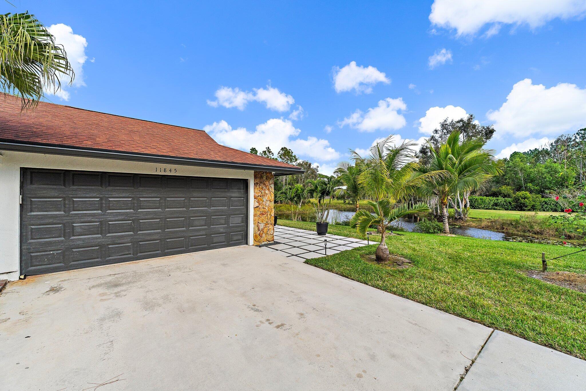 11845 165th Road North Jupiter, FL 33478 - Photo 9 of 68 a front view of a house with a yard and garage