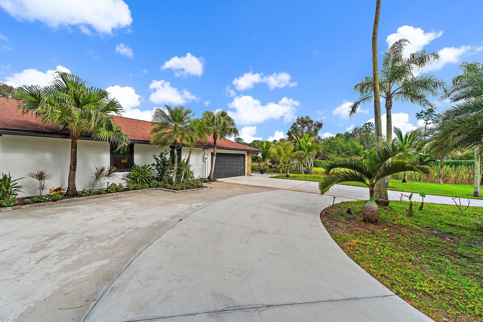 11845 165th Road North Jupiter, FL 33478 - Photo 10 of 68 a front view of a house with a yard and a garage