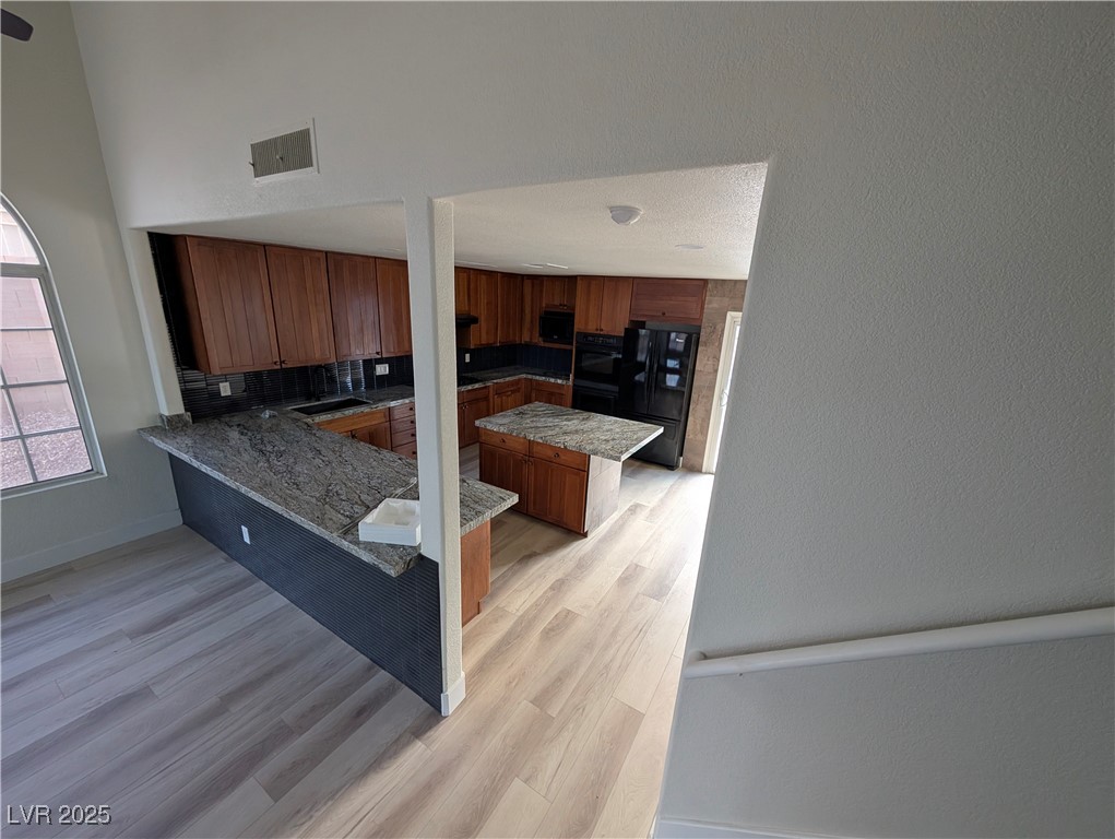 104 Appian Way Henderson, NV 89002 - Photo 13 of 52 Kitchen with a kitchen bar, a kitchen island, black appliances, and brown cabinets
